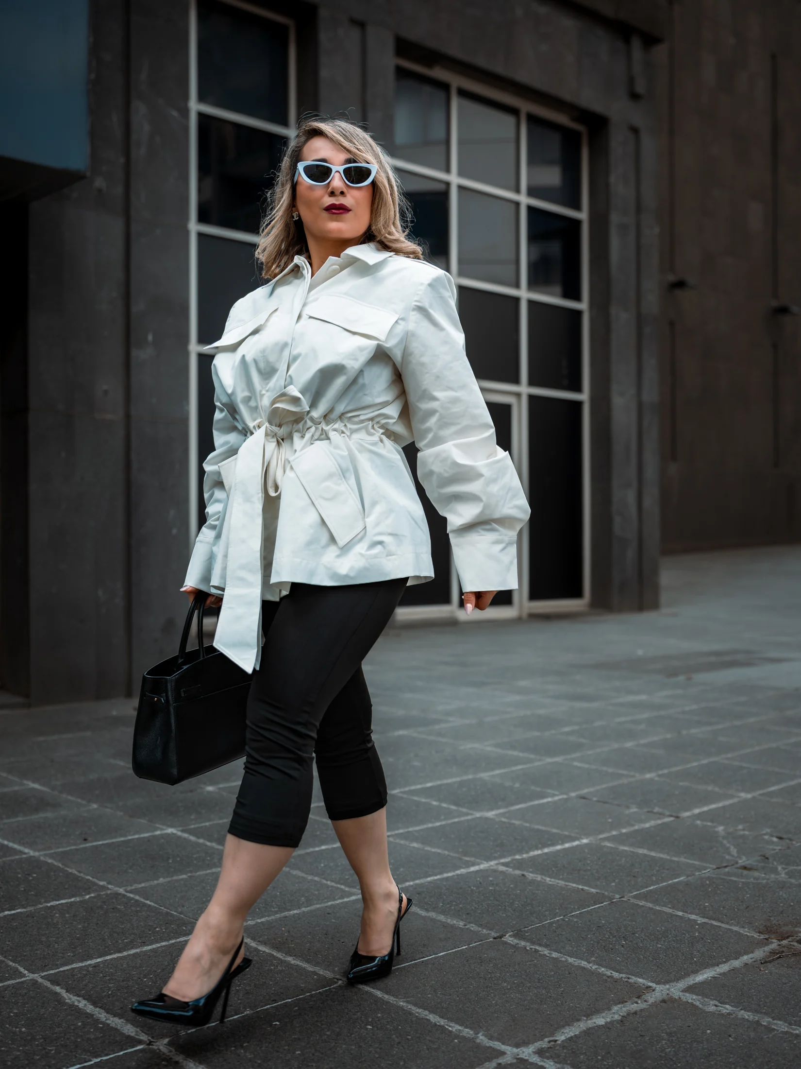Neda in a white jacket, black capri trousers and heels on a Melbourne street