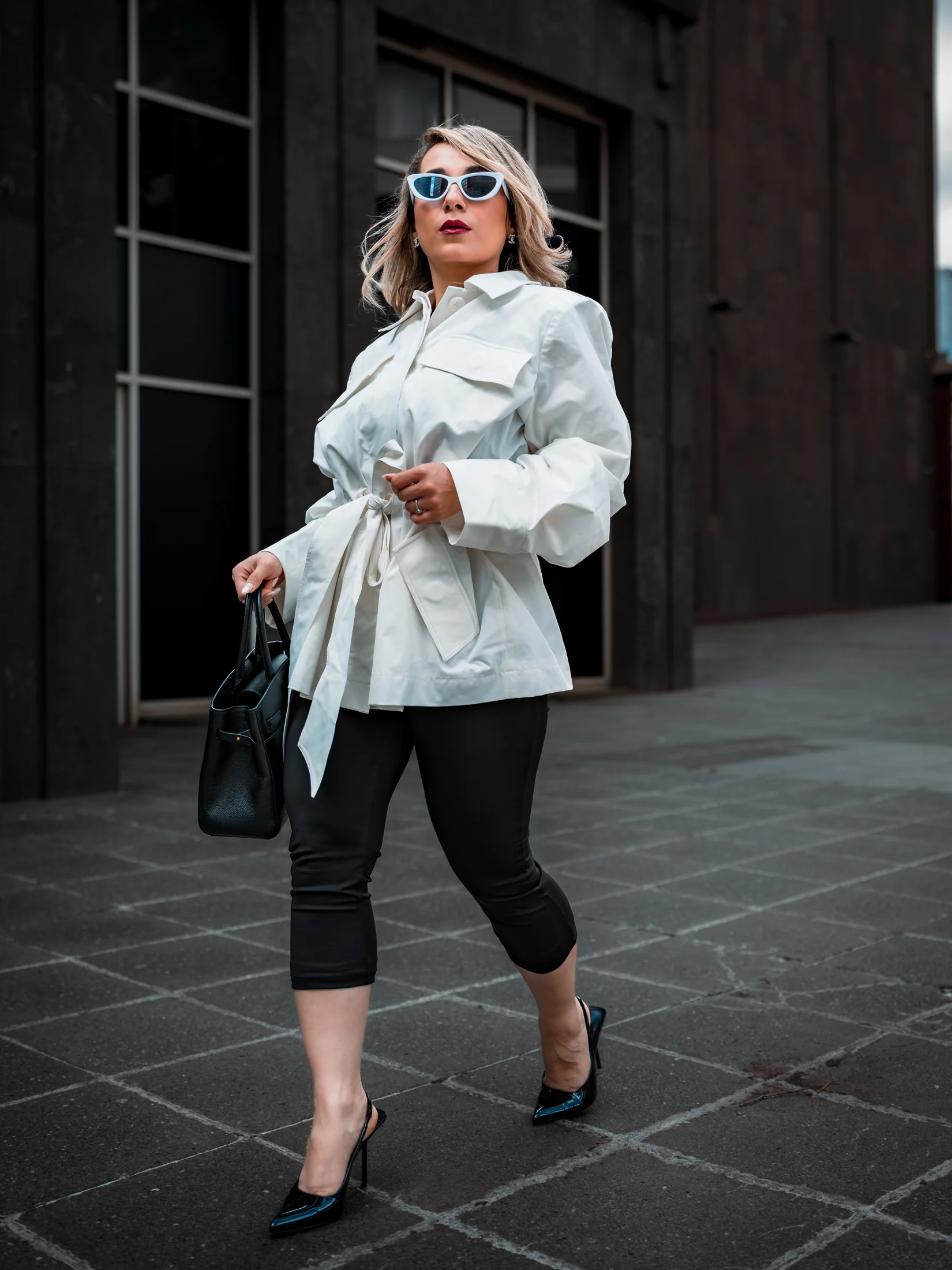 Neda styling a white belted jacket with a black handbag and pointed heels