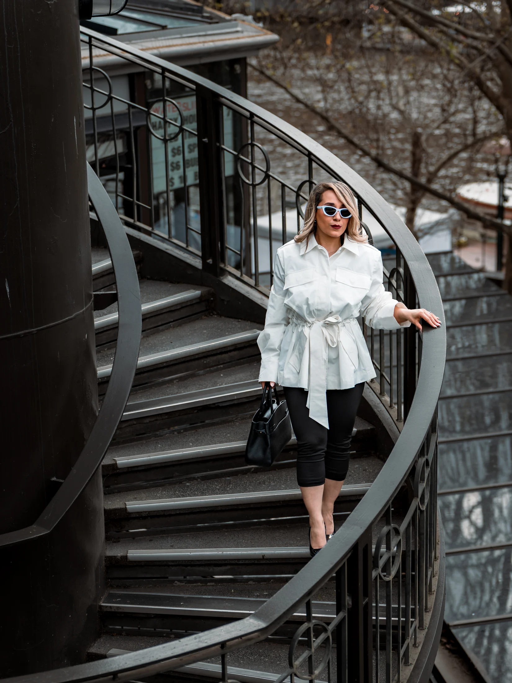 Neda in a white jacket standing on an outdoor Melbourne staircase